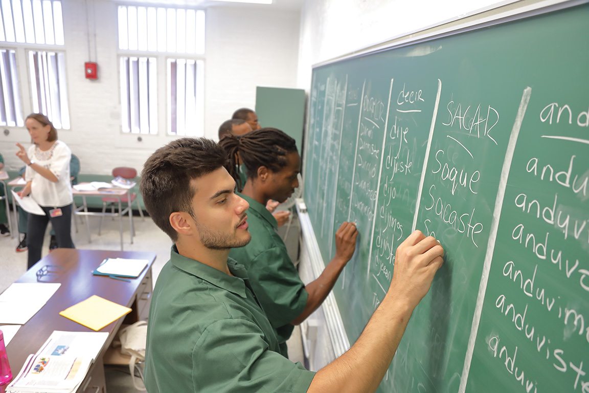 Eastern inmates Alexander Hall (foreground) and Rodney Spivey take to the chalkboard for another language drill in the Intermediate Spanish 1 class taught by Bard College Professor Melanie Nicholson.