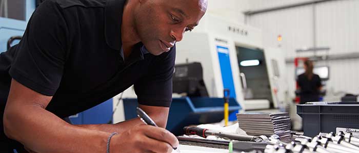 Engineer Planning Project With CNC Machinery In Background