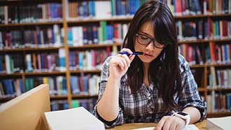 Stock photo: student in library, pencil in mouth