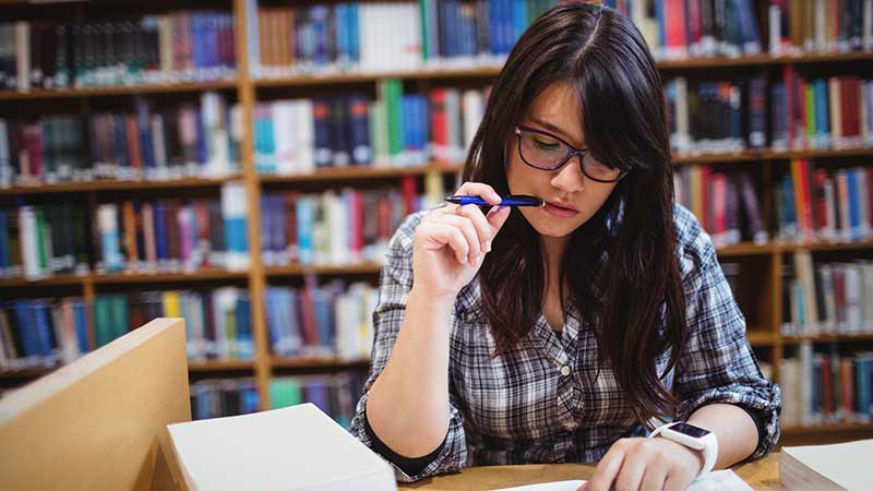 Stock photo: female student studying, pencil in mouth