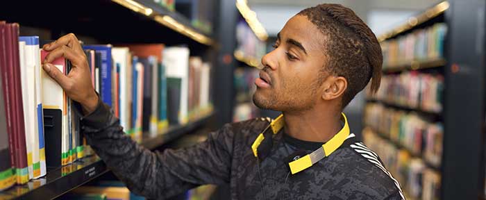 Black student exploring library stacks