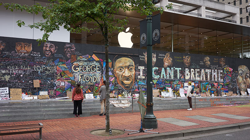 Portland, OR, USA - Jun 12, 2020: Passers-by stop and take a look at the boarded-up Apple Store in downtown Portland's Pioneer Place, which has become unofficial canvases for peaceful protest. Artists have also joined to promote peace over violence.