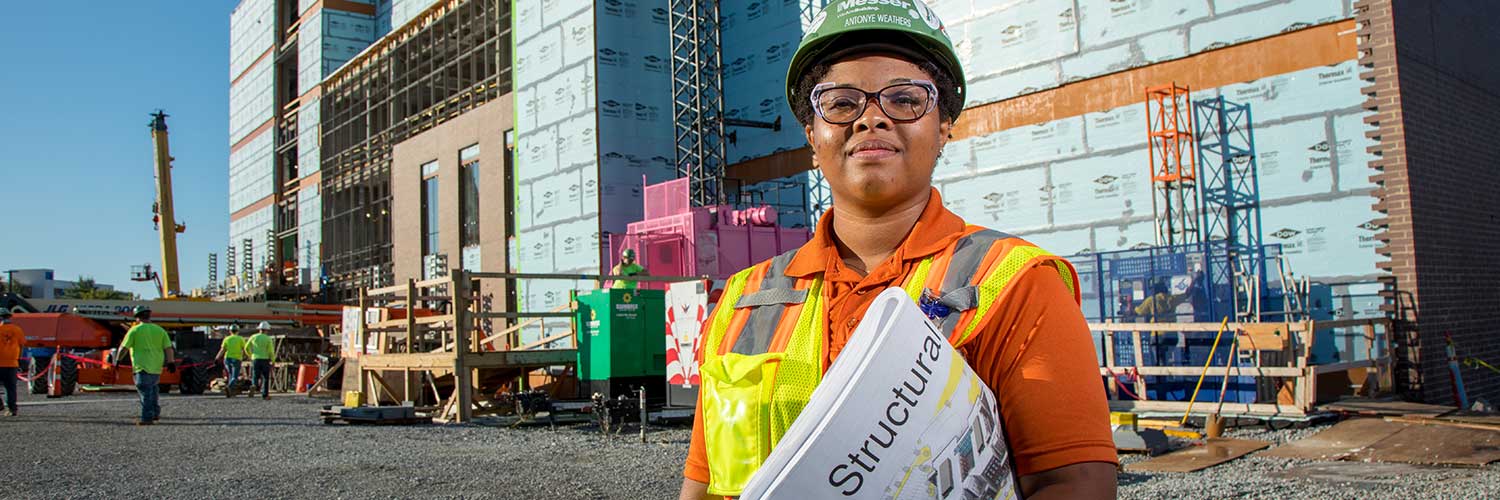 Messer employee Antonye Weathers in front of building site holding structural diagrams.