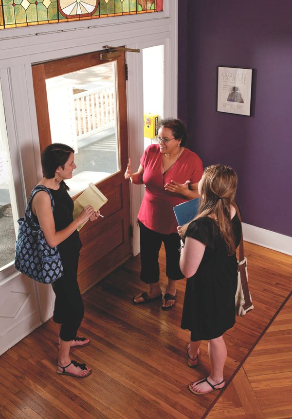 Anita DeRouen, assistant professor of English at Millsaps College talks with student mentors in a high-ceilinged atrium.