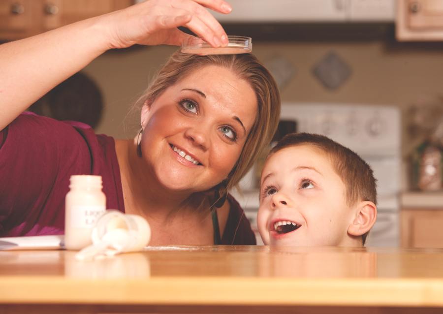 Shannon Adams of Martinsville, Ind. peers up into a petri dish in the light. He 5-year-old son looks up in clear fascination and delight.