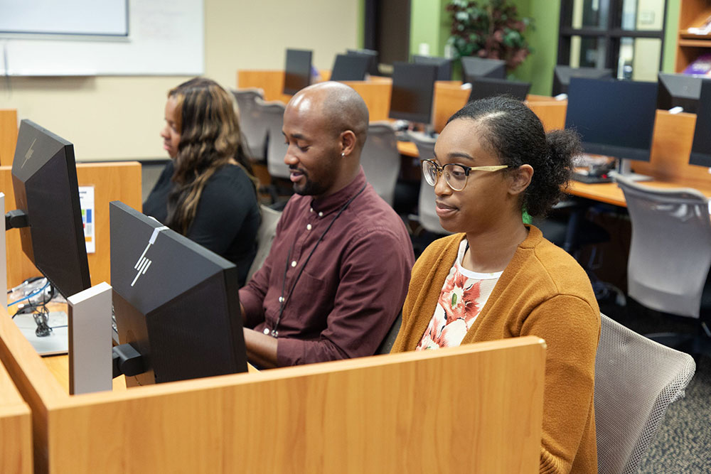 Three Black students at workstations at the CLD.