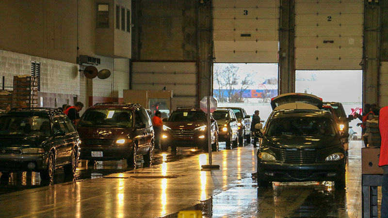 Two lines of cars wait for service in a high-ceilinged concrete hangar.