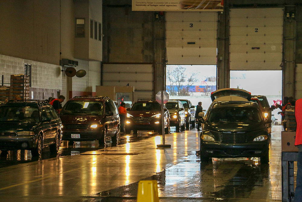 Two lines of cars wait for service in a high-ceilinged concrete hangar.