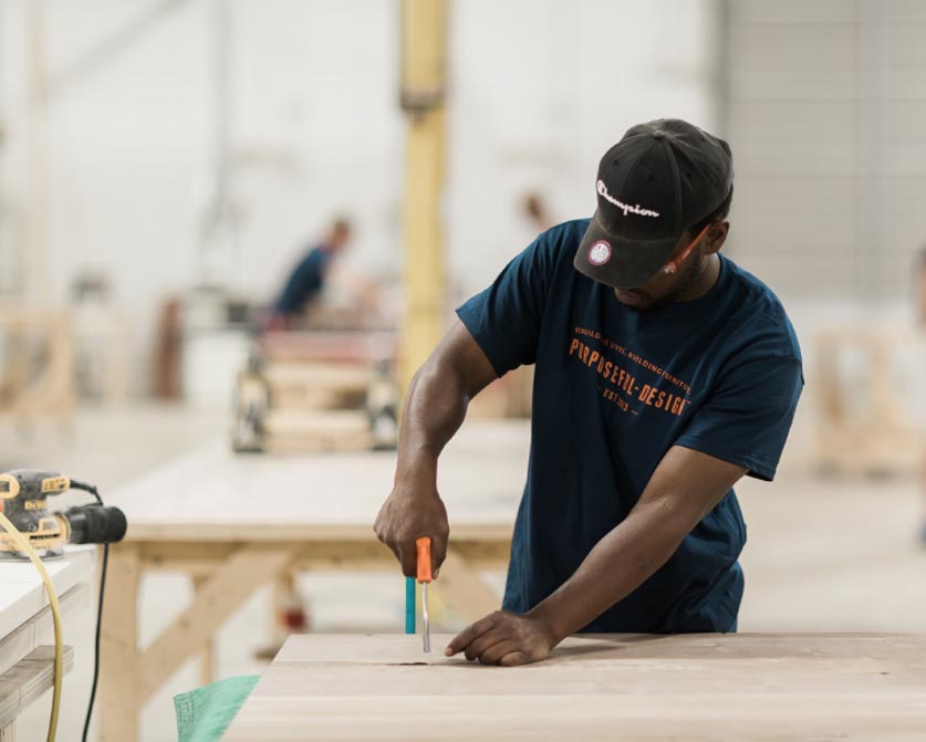 Black woodworker in Purposeful Design t-shirt using a hand tool.