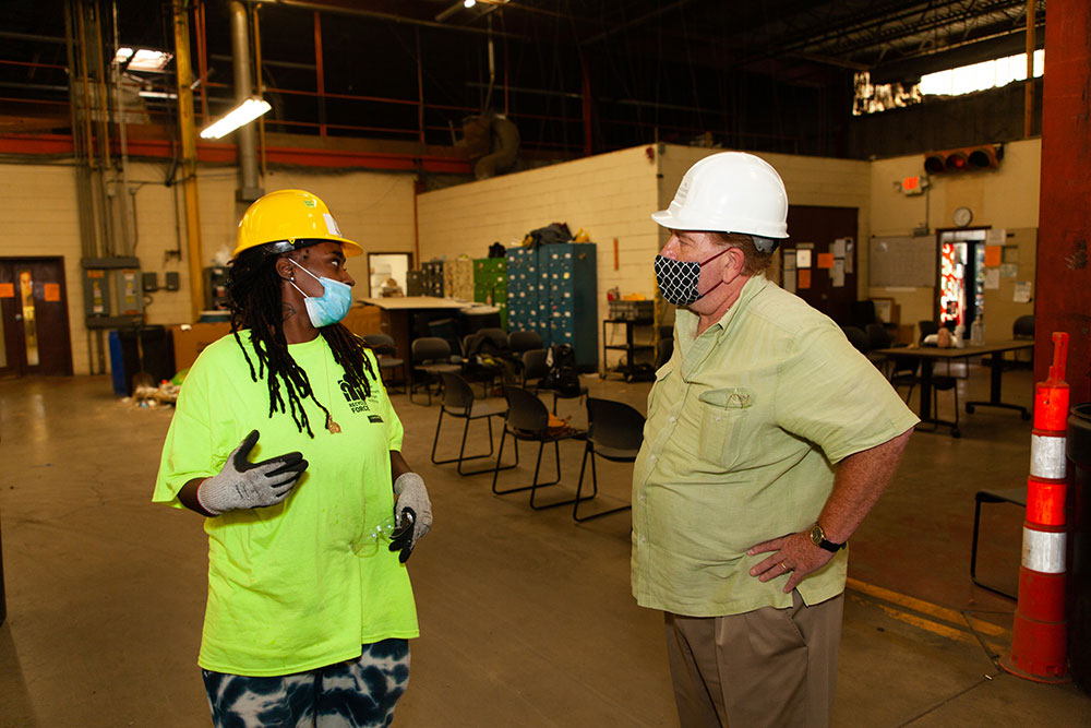 Workers in hard hats and COVID masks having a discussion in a work environment.