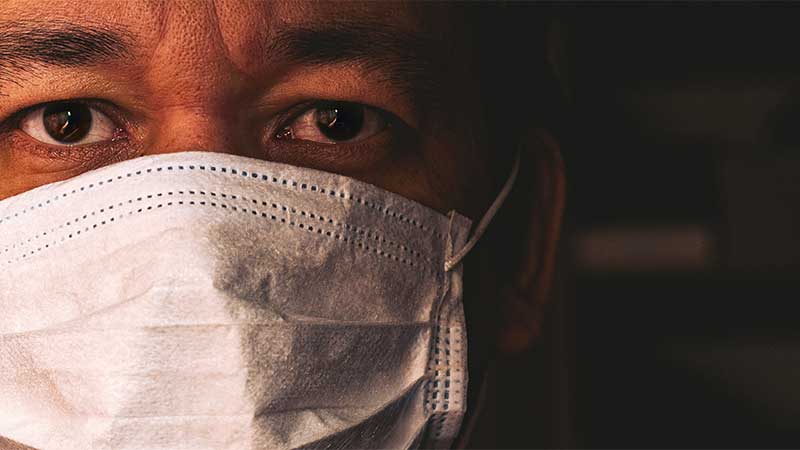 Close up of Black doctor's face mostly covered by a COVID mask.