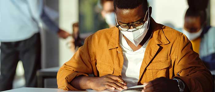 Black student reading and wearing COVID mask.