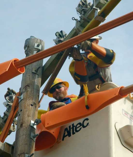 Two workers in a cherry picker working on line poles.