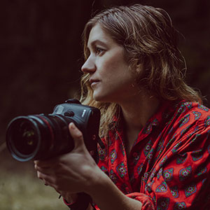 Photographer Rachel Bujalski holding her camera, apparently poised to take a shot.