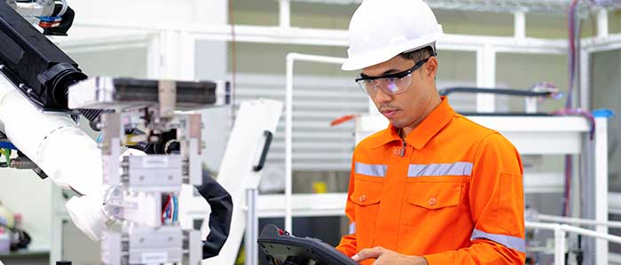 Worker in orange safety suit and helmet operating machinery