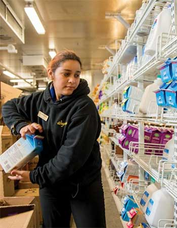 Female worker loading up almond milk in a grocery environment.