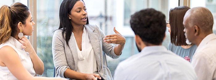 Black woman leading a roundtable discussion.