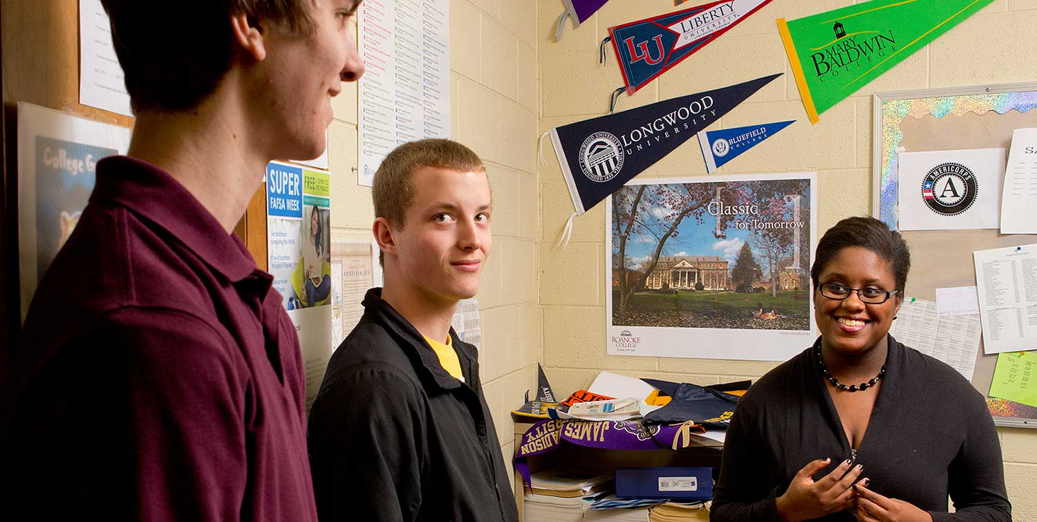 College adviser Erica Elder confers with seniors Orin Bye (far left) and Austin Wright at her alma mater, Bassett High School in southern Virginia. Elder, a recent graduate of the University of Virginia, returned to Bassett recently to serve as a near-peer mentor for an organization called the College Advising Corps.