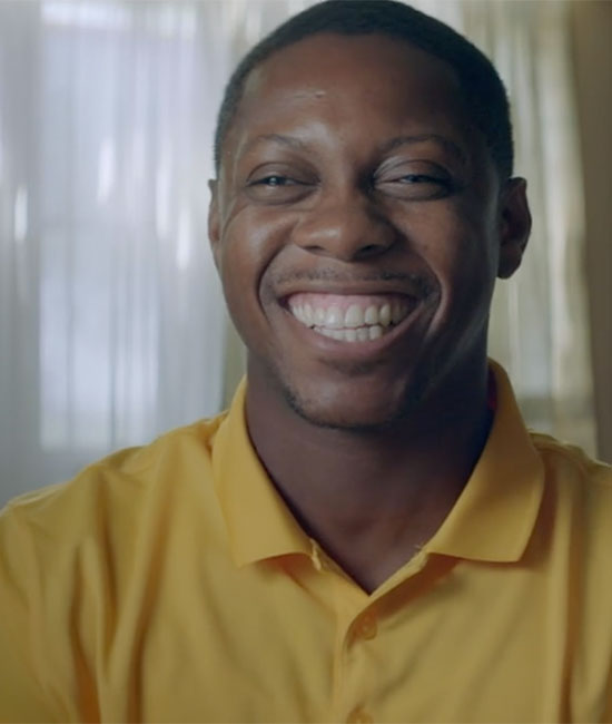 Video still: Dante in a yellow shirt smiling.