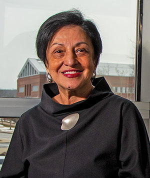 Elsa Núñez seated in front of a window, buildings in the background.