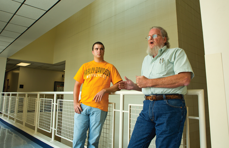 An administrator and student lean against a handrail.