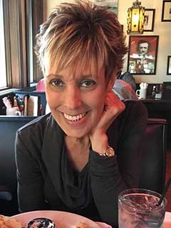 Kimberly, smiling, in a restaurant setting.