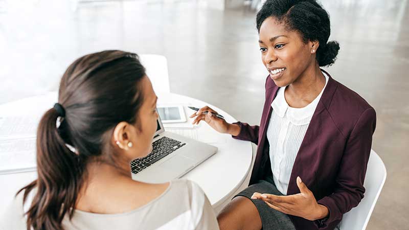 Two women work together in an office environment.