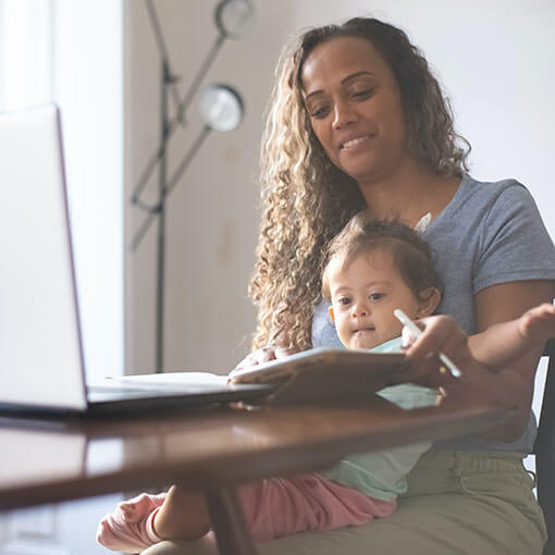 Mother with child in her lap. She appears to be studying.