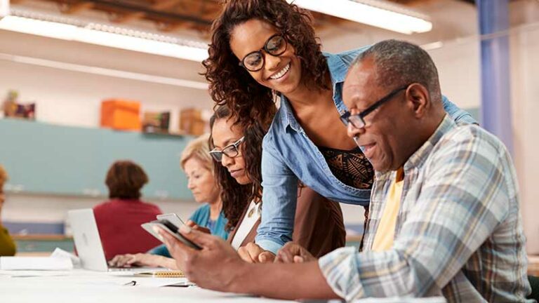 Adult student working at a desk with someone who appears to be mentoring him.