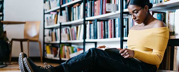 Black female student studies in a library.