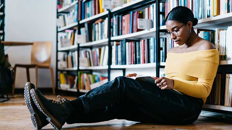 Black female student studies in a library.