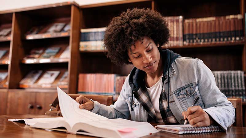 Black student studies in a library environment.