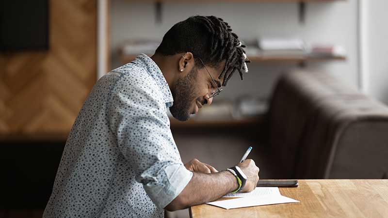 Black man writing at a desk.