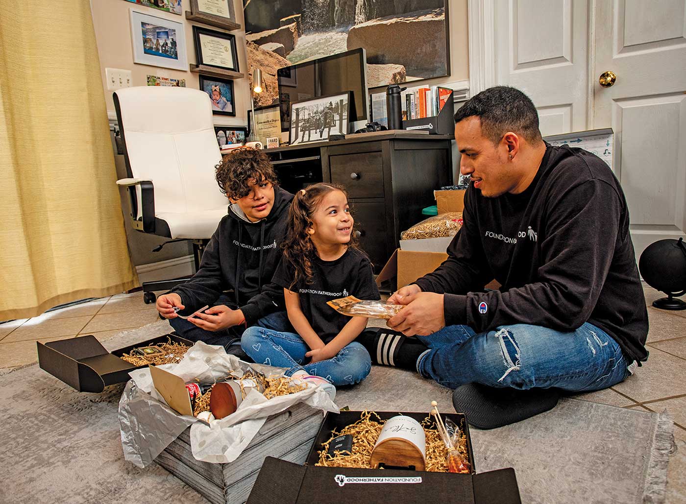 Ariel with his two children packaging boxes on the floor.