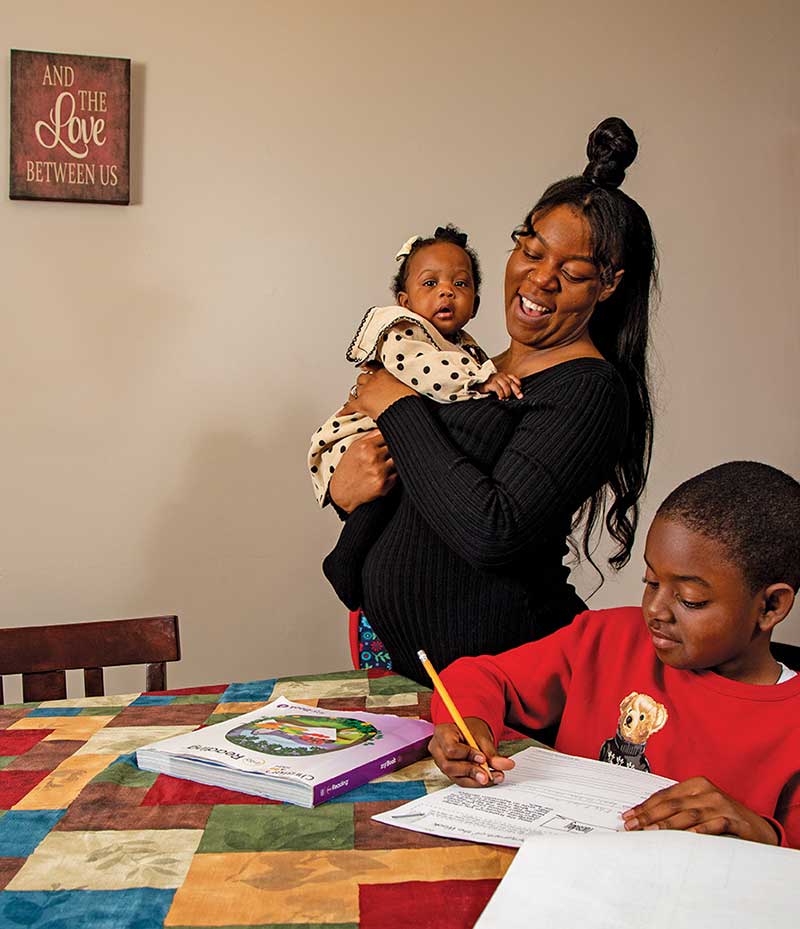 At her home in Byron, Georgia, Sanataty Nottingham holds 6-month-old daughter Sanaa Canady while helping son Christian Canady, 9, with his math homework. She cites her own children as one reason she’s determined to achieve her higher education goals. “I want to do it for them,” she says, “just to show them that if I can do it, they can, too.”