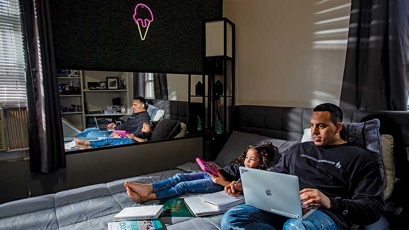 Father and daughter study together in bed.