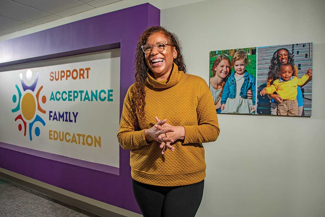 Nicole Lynn Lewis standing in her workplace, smiling.