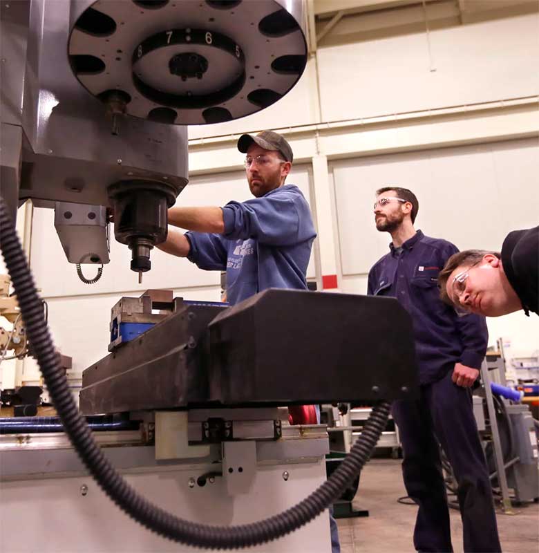 Workers posing by some high-tech industrial gear.