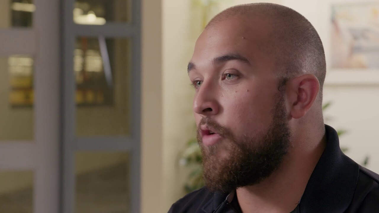 One of the brothers featured in the video is interviewed. His workplace is visible in the background.