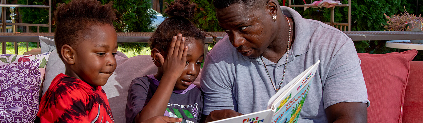 A father is reading “The Ugly Duckling” to his young children.