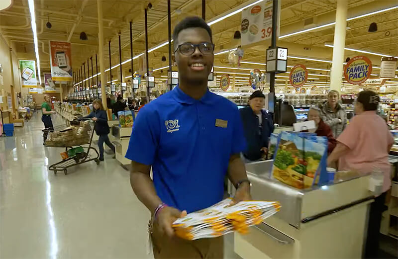 Video still shows young Wegman employee, looking satisfied.