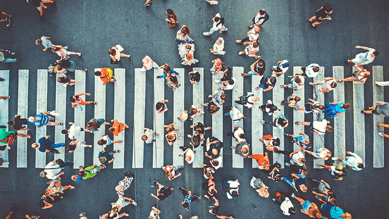 Arial shot of crowd walking on downtown crosswalk.