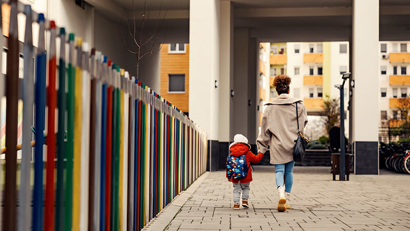 Mother walks with child on public sidewalk.