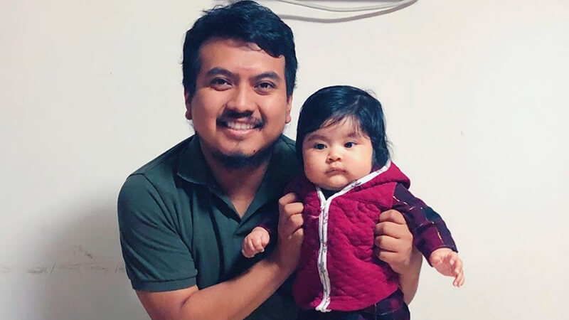 Edgar Lopez holding his niece. He is smiling. She is adorable.