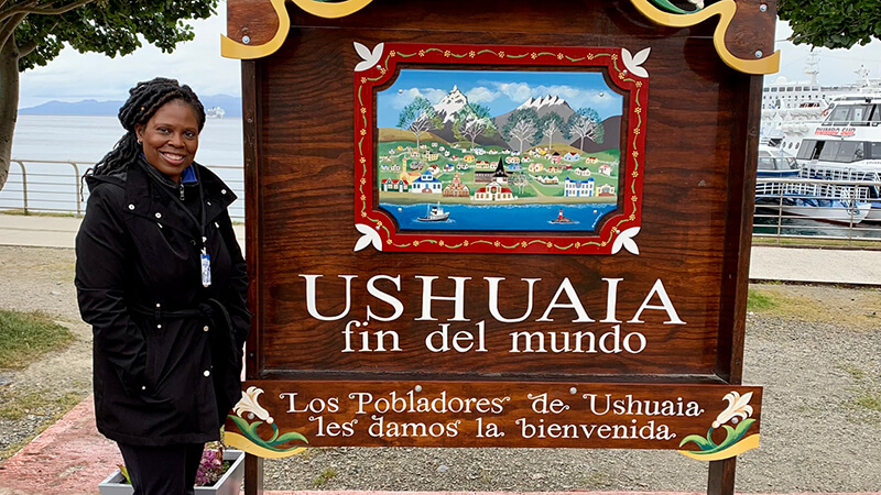 Susan Johnson posing next to an Uhsuaia sign.