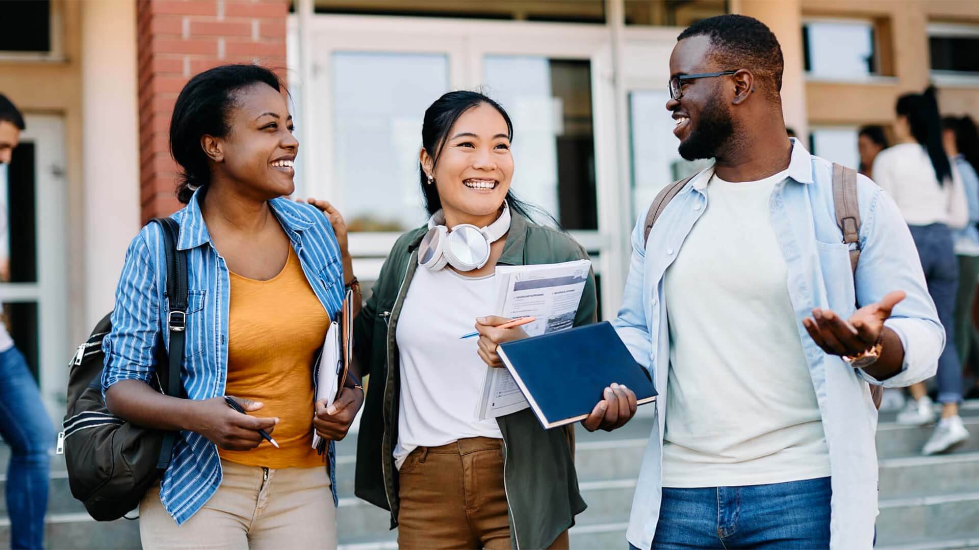 3 students talking and walking on campus