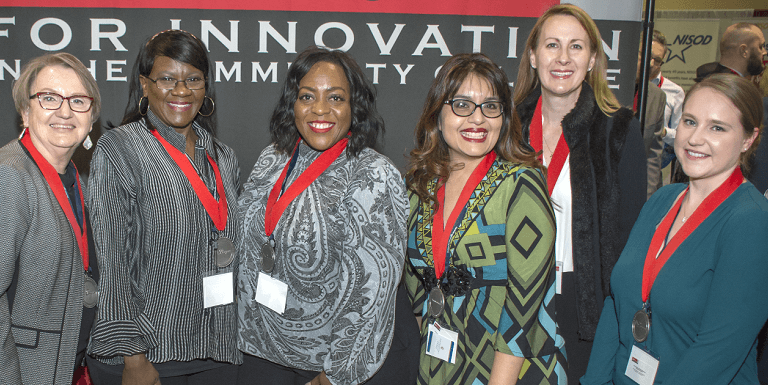 bunch of education leaders with lanyards in front of a sign saying something about innovation