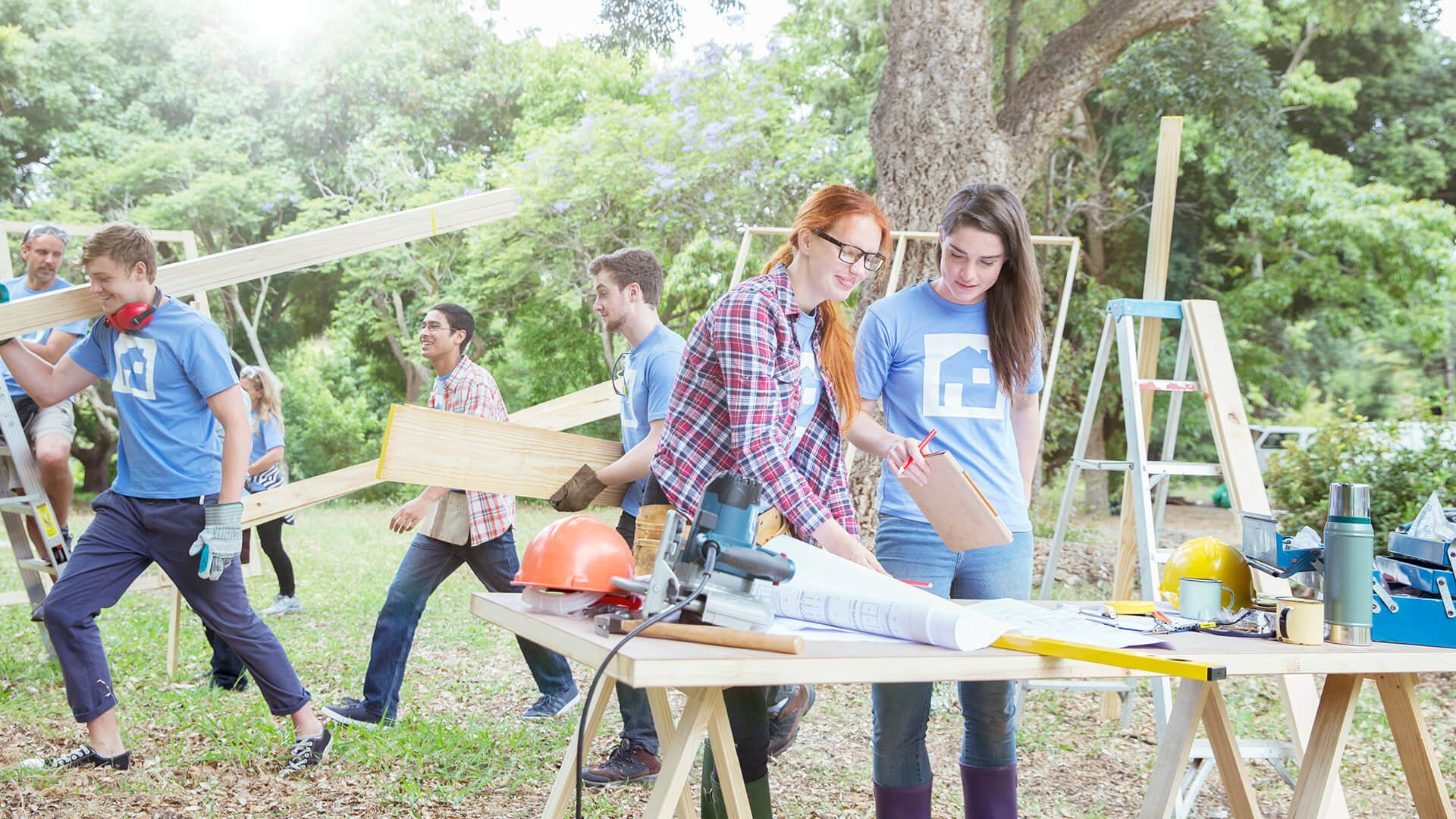 Happy volunteers lifting wooden frame together at park stock photo