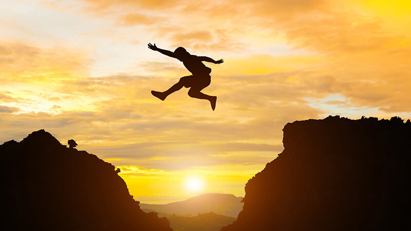 Man jump mountain cliff morning mountain sky and over silhouette stock photo